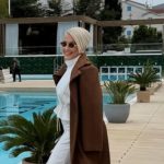 Indira Levak bila je specijalna gošća nesvakidašnjeg modnog događaja “JOAN x GLAS MODE”, koji je okupio brojne zvanice iz svijeta mode, umjetnosti i javnog života. Za ovu priliku, pjevačica je odabrala elegantnu i efektno osmišljenu bijelu kombinaciju koja je odmah privukla pažnju prisutnih. Nosila je uski kombinezon sa dugim rukavima i naglašenim strukom, koji je u potpunosti pratio liniju njenog tijela i ostavio utisak sofisticiranog i modernog stila. Poseban detalj stajlinga bio je dugački plašt, odnosno šlep u svijetloj, nježnoj nijansi, koji se spuštao iza nje i cijelom izdanju davao dozu glamura i scenskog efekta. Upravo taj modni element dodatno je naglasio eleganciju i ekskluzivnost njenog pojavljivanja. Kombinaciju je upotpunila svedenim aksesoarima i elegantnom frizurom sa kratkom plavom kosom, čime je cjelokupan izgled dobio luksuzan i izrazito damski karakter. Hype televizija stigla je na crnogorsko primorje, odakle donosi ekskluzivne kadrove i jedinstvenu atmosferu sa prestižnog modnog događaja koji će u narednim danima okupiti brojna poznata imena iz svijjeta mode, medija i biznisa.